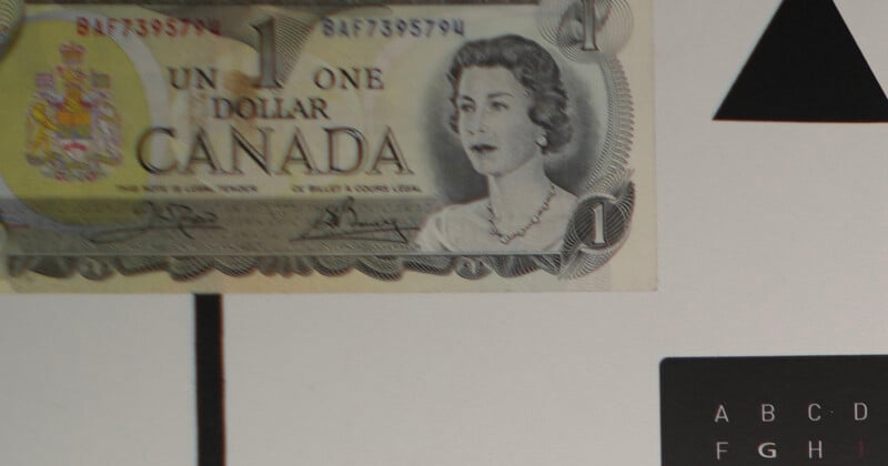 A Canadian one dollar bill featuring a portrait of Queen Elizabeth II is placed on a white and black geometric background with letters and shapes partially visible.