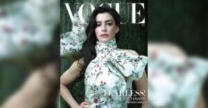 A woman in a floral, high-neck dress poses in front of a dark green backdrop on the cover of Vogue magazine, with the headline "FEARLESS!" and the name Anne Hathaway featured prominently.