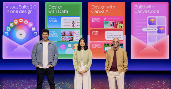 Three people stand on a stage in front of colorful presentation slides about Canva tools, including Visual Suite 2.0, Design with Data, Design with Canva AI, and Build with Canva Code. Confetti is scattered on the floor.