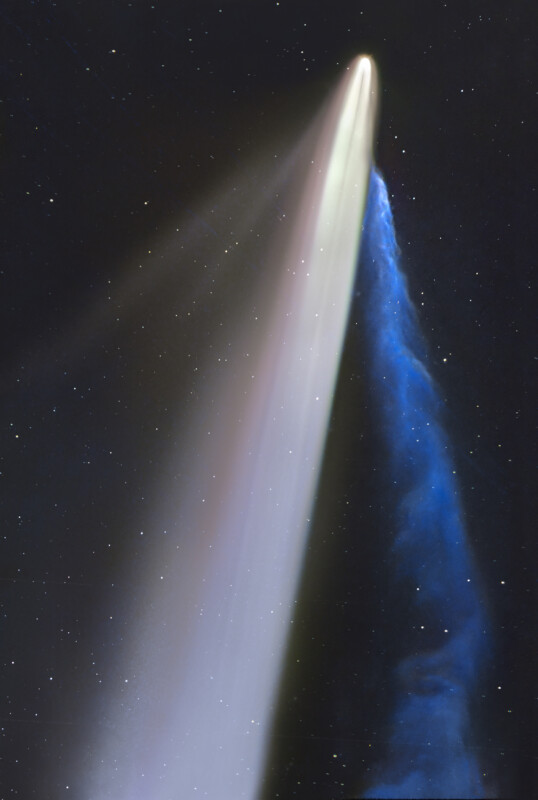 A bright comet streaks through space, displaying a wide white dust tail and a narrow blue ion tail against a dark, star-filled background.