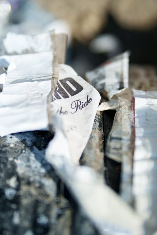 A close-up photo of crumpled, torn pieces of paper with partially visible, blurred text reading "the Ride" among various scattered debris.