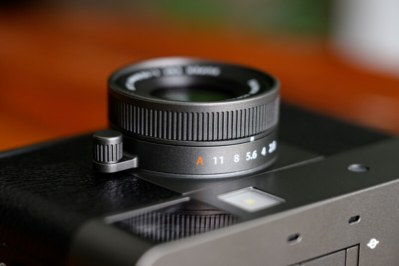 Close-up of a camera lens showing the aperture ring with settings from f/2.8 to f/11, and an orange "A" for auto mode, mounted on a black camera body.