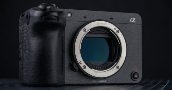 A close-up of a Sony Alpha full-frame mirrorless camera body without a lens, showing the E-mount and sensor, placed on a dark surface with a black background.