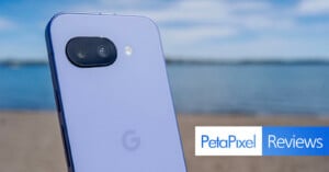A close-up of a purple smartphone with dual rear cameras, taken outdoors near a beach, with the PetalPixel Reviews logo in the bottom right corner.