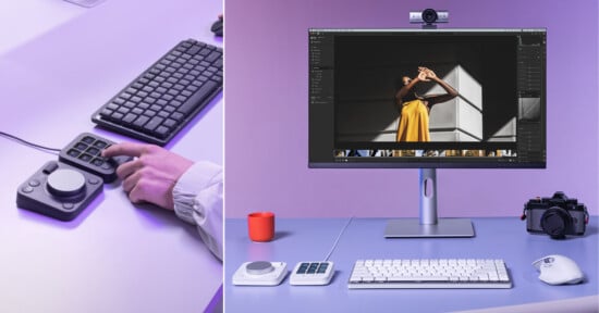 A person uses a photo editing console next to a keyboard. Nearby, a tidy desk setup includes a monitor displaying a photo, a camera, editing consoles, a keyboard, a mouse, and a red cup under purple lighting.