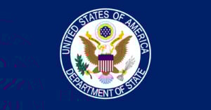 The official flag of the U.S. Department of State featuring the department’s seal: a bald eagle with a shield, holding an olive branch and arrows, surrounded by a blue background and the text "United States of America Department of State.