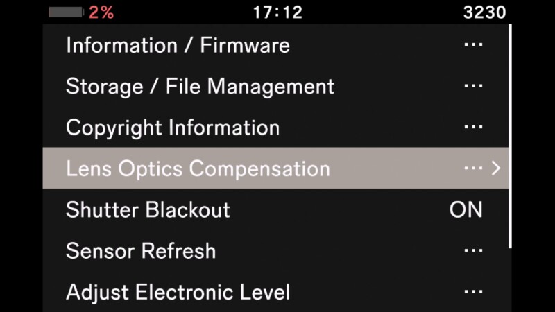 Camera settings menu displaying options including Information/Firmware, Storage/File Management, Copyright Information, Lens Optics Compensation (highlighted), Shutter Blackout, Sensor Refresh, and Adjust Electronic Level. Time displayed is 17:12.