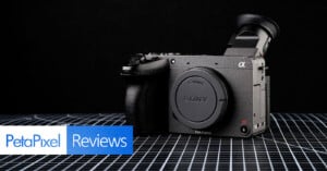 A Sony Alpha full-frame mirrorless camera is displayed on a grid-patterned surface with a dark background. The PetaPixel Reviews logo is overlaid in the bottom left corner.