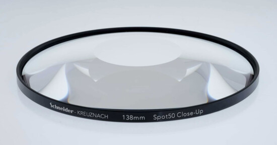 A close-up view of a Schneider-Kreuznach 138mm Spot 50 Close-Up lens filter. The filter is circular with a black rim displaying its specifications, and is placed on a neutral background.